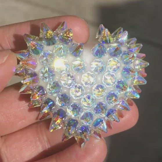 A video showing Bunny Paige's Classic Crystal Spiked Heart created by Cleveland artist, Lauren Tatum. The handmade white resin heart is covered with iridescent Swarovski crystal spikes that sparkle with a rainbow color shift in the afternoon sunlight.